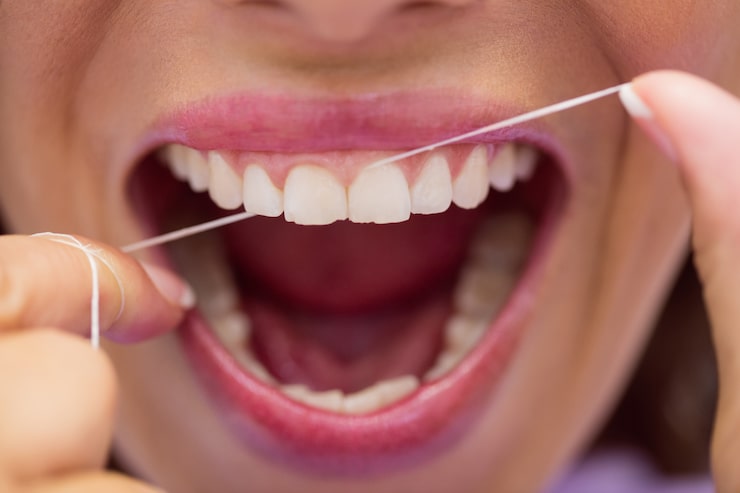 Woman flossing her teeth as part of a daily oral hygiene routine